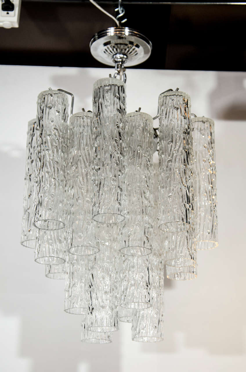 Modern chandelier with multiple tier design, comprised of hand blown Murano glass cylinders with a chrome frame and fitings.  The cylinders have a tubular form with textured relief pattern. There are 22 glass cylinders which hang at varying heights.