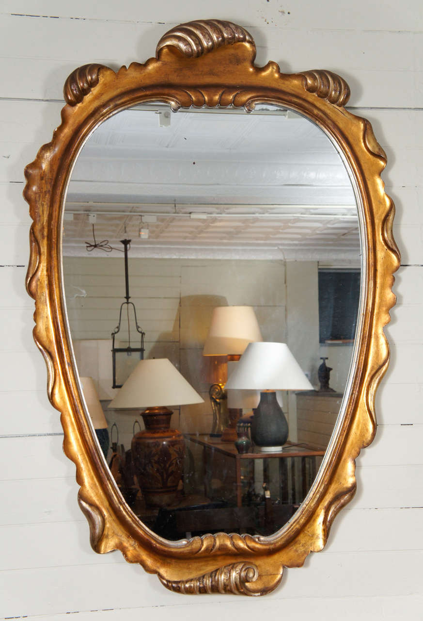 Elegant single mirror, with gilt, carved wooden frame. produced by Dorothy Draper Inc.  Hand applied gilding in several soft tones, with an inviting open glass plane.