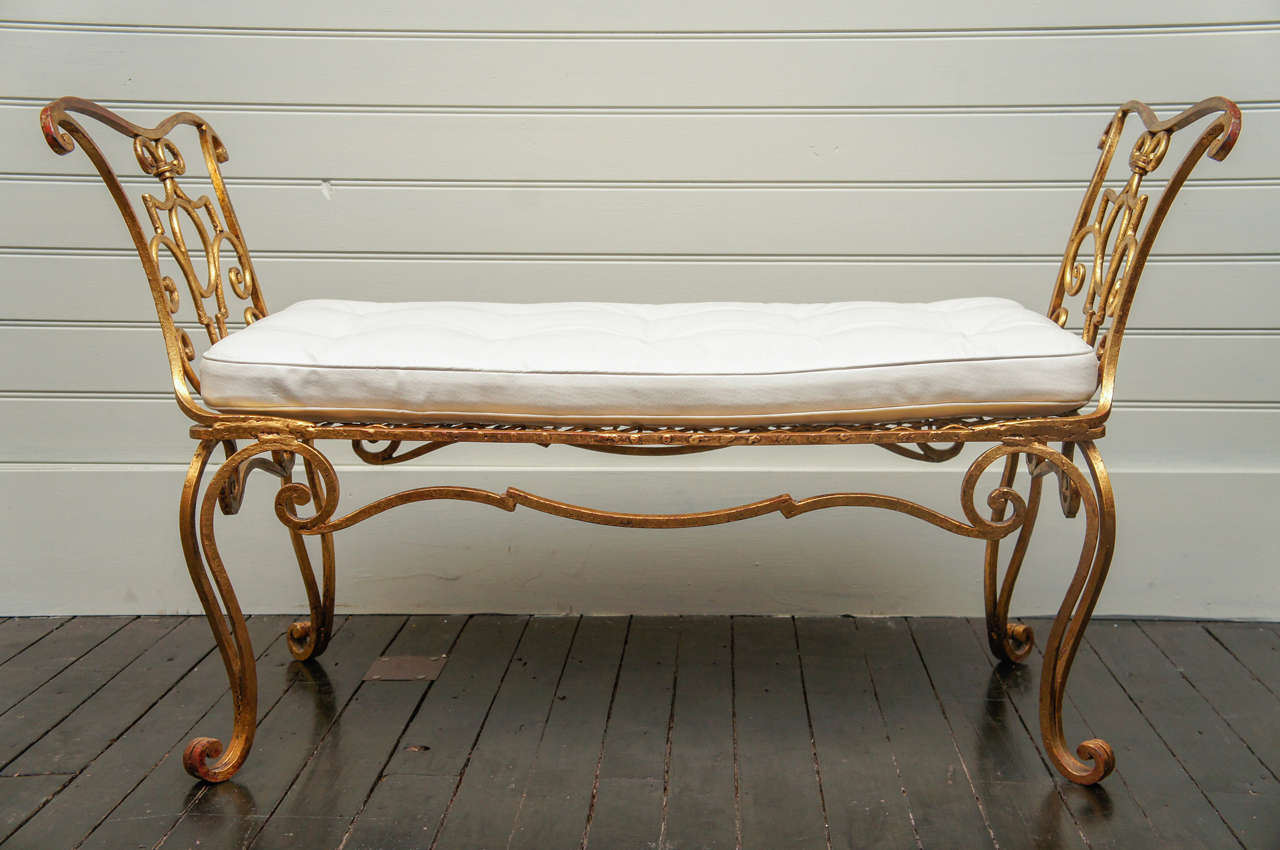 Single wrought iron bench, with gilt surface, produced and designed by Jean Charles Moreaux, in the Regency taste. Paris France, in the 1940's. Complimented by a detatched white leather seat cushion.