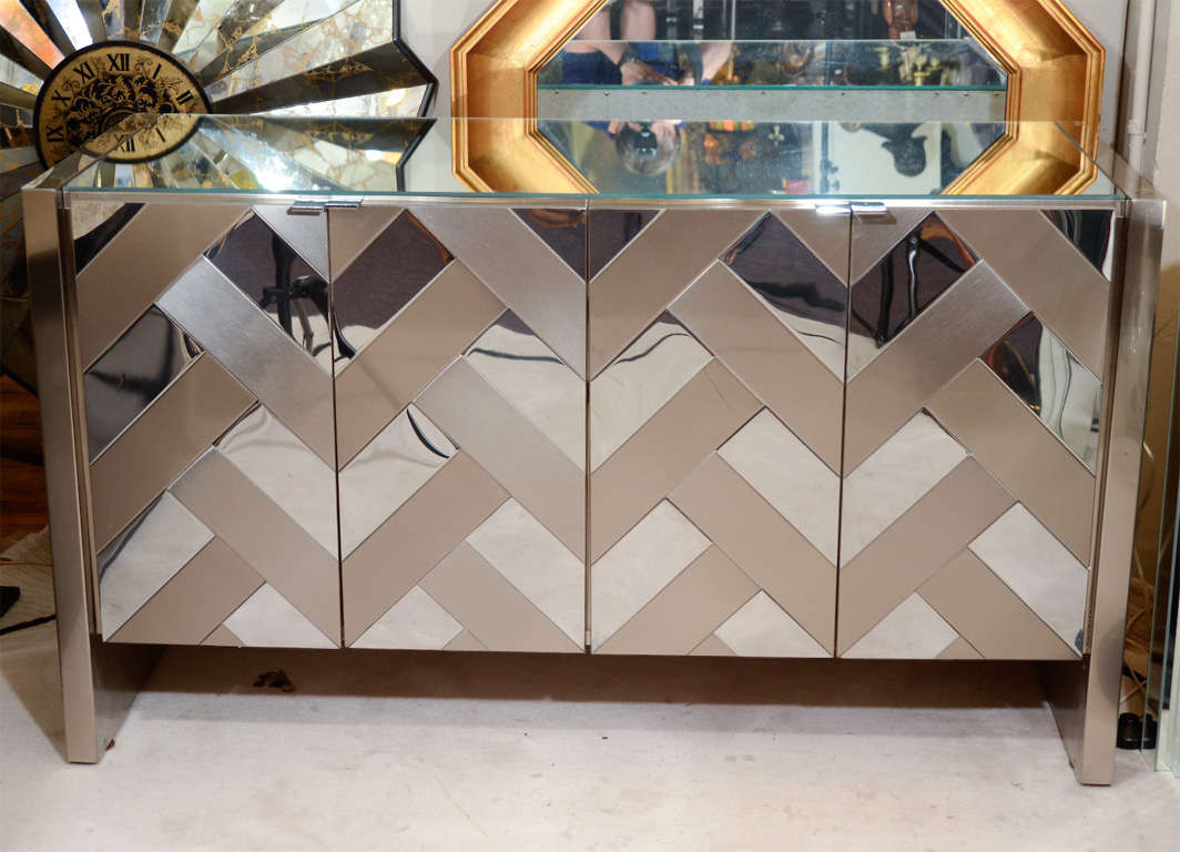 A vintage sideboard by Ello Furniture co. with a mirrored top, brushed metal sides and mirrored and brushed metal chevron pattern tiles on the doors.