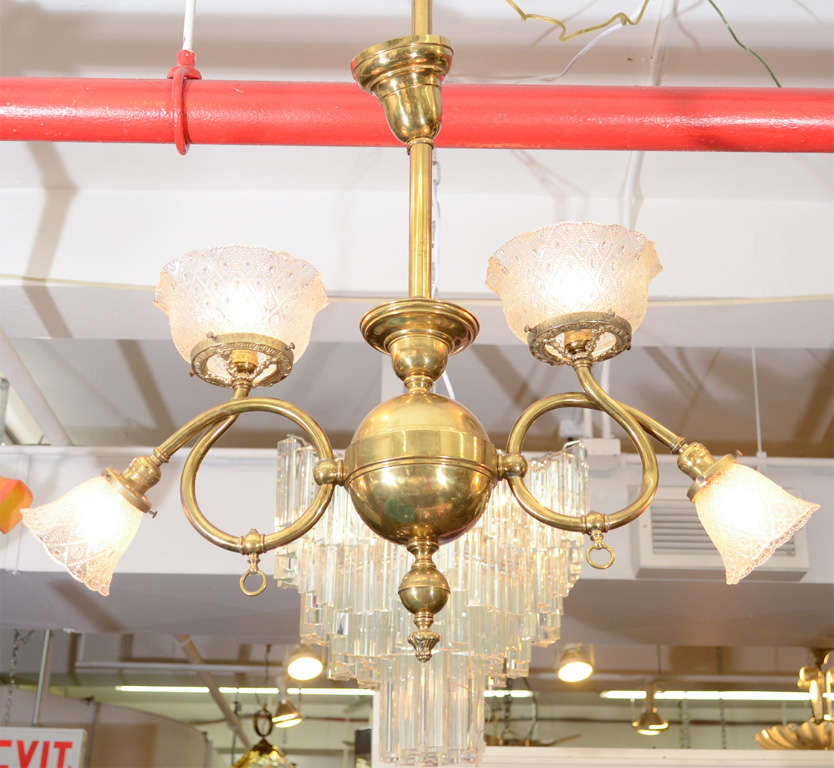 An antique Victorian chandelier with a brass body and original glass shades. The piece was originally gas powered but has been recently electrified.