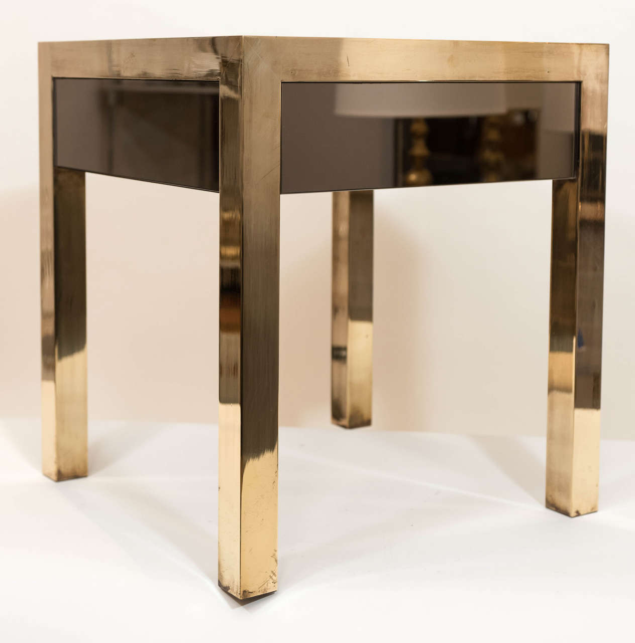 A richly patinated and polished pair of brass and bronze mirrored end tables 
with flush mounted front drawer. These solid brass tables are from a prominent Montreal home and date from the early 1970's.