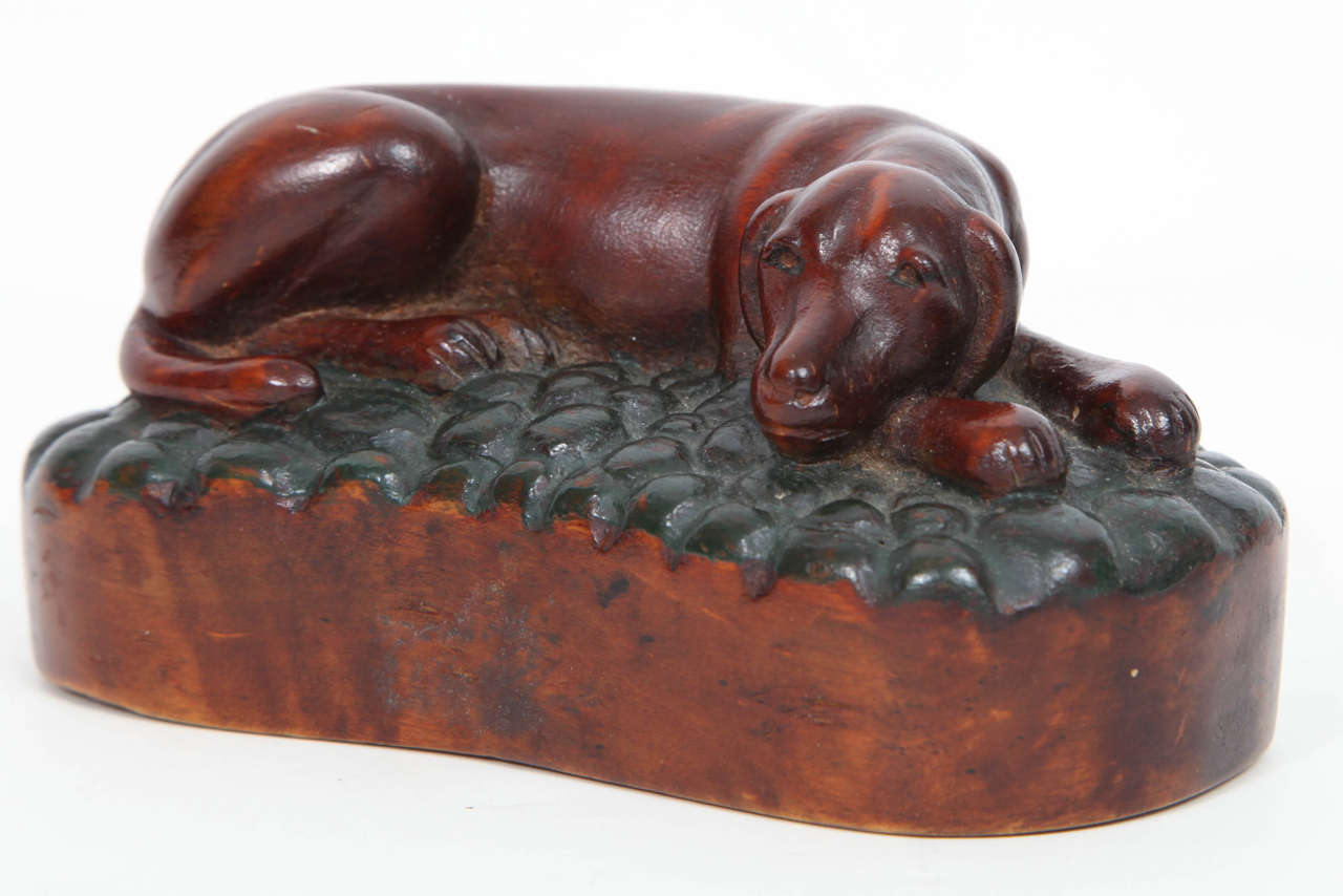 A Swedish carved and painted birchwood recumbent dog, Late 19 Century.