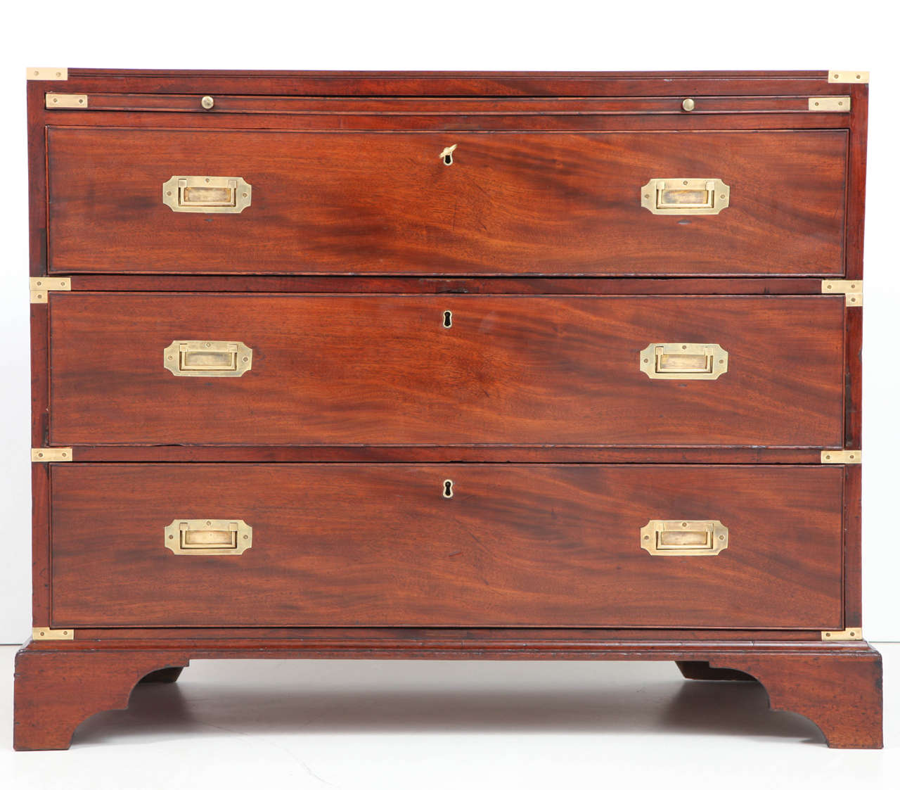An English brass mounted mahogany campaign chest of drawers, circa 1870s, in two parts with a slide out writing surface above three long drawers raised on bracket feet.