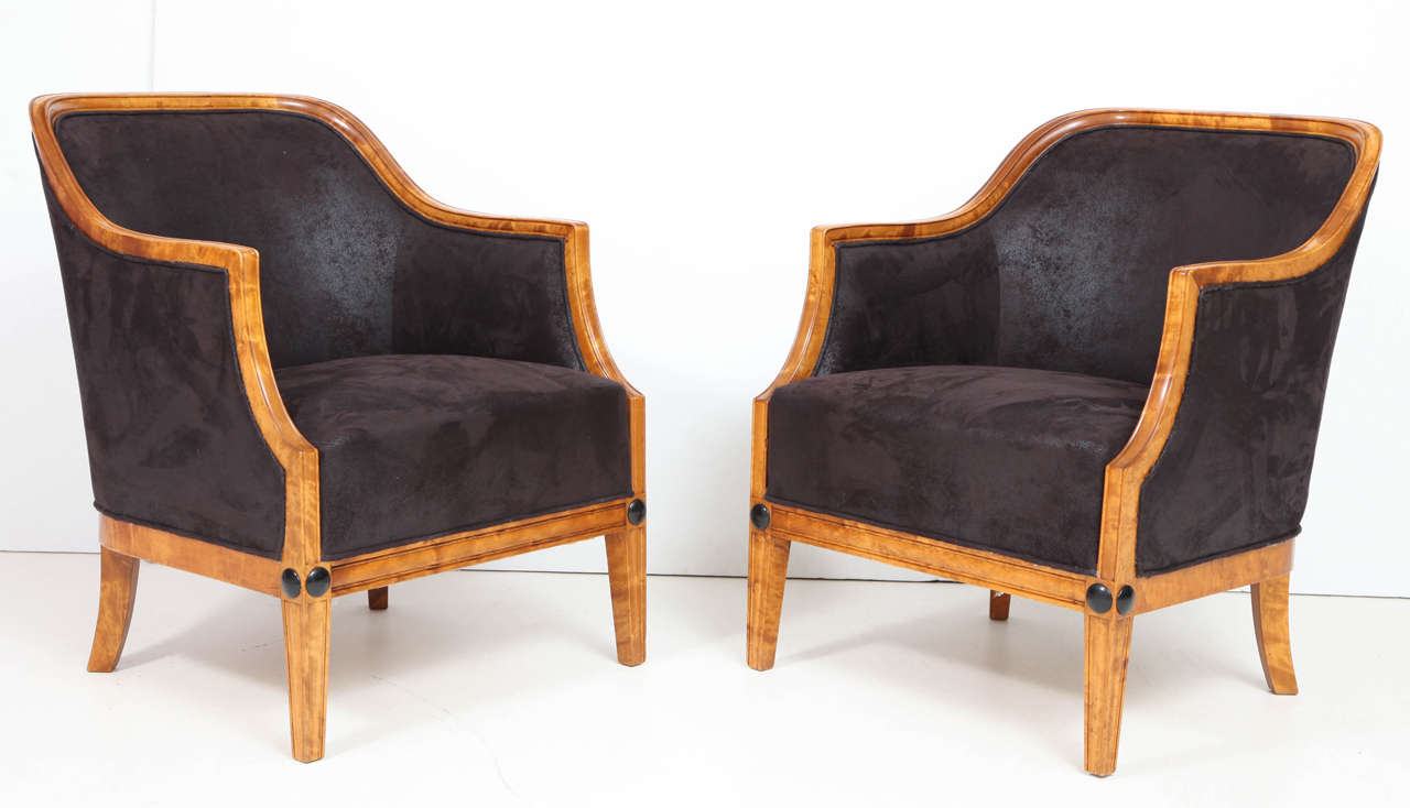 A pair of Swedish birchwood and ebonized full size armchairs, Circa 1930-40, with a curved back, sweeping armrests raised on square tapered legs headed with ebonized roundels.