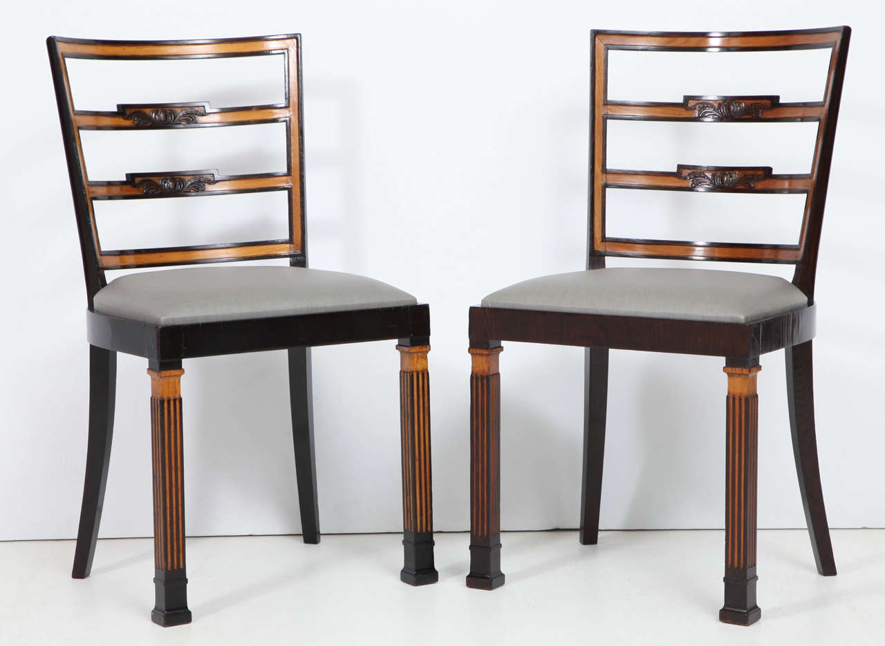 A set of ten Swedish elmwood and ebonized chairs by Erik Chambert Chairs, Circa 1940, comprising of 10 side chairs each with a curved ladder back with carved splats, drop-in upholstered seats, raised on square fluted legs with block feet.