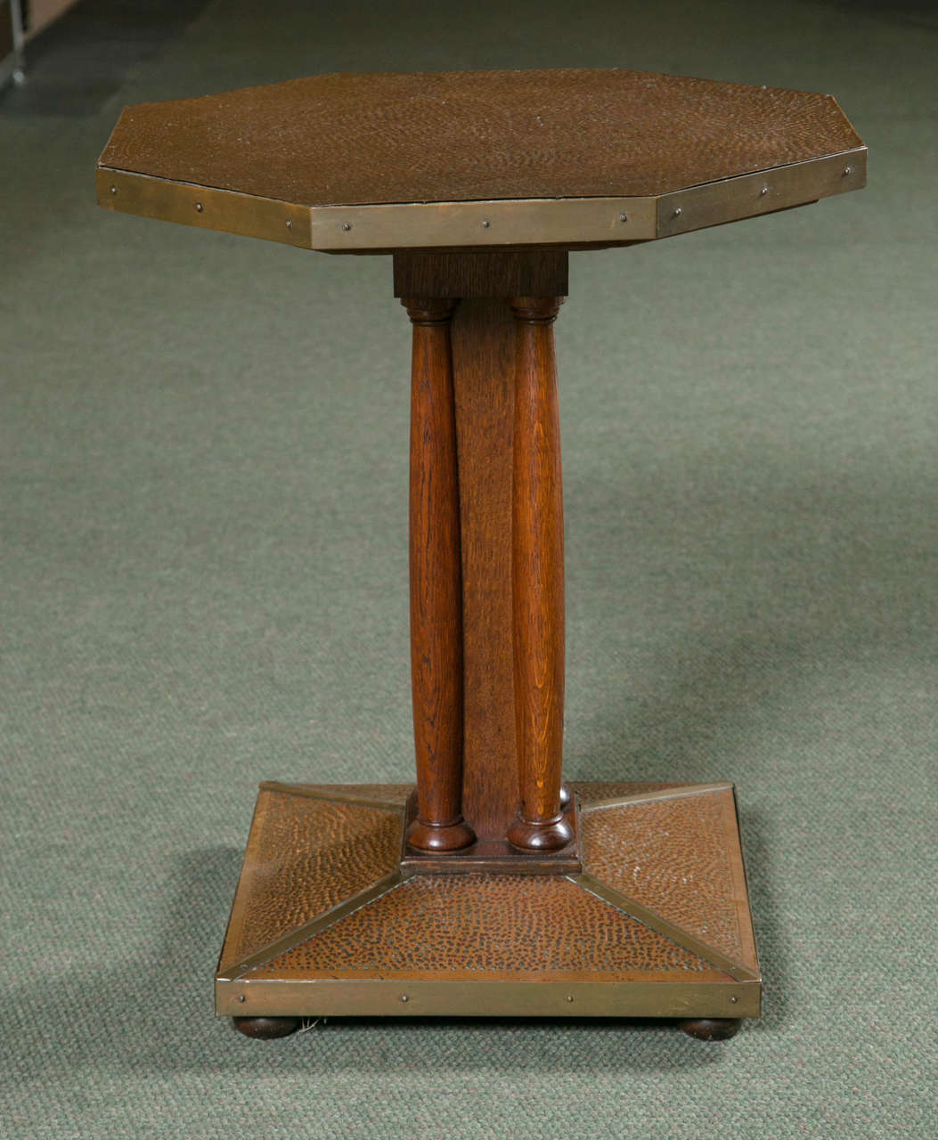 An Arts & Crafts octagonal table with hammered copper top and base and wood pedestal in the style of Hoffman.