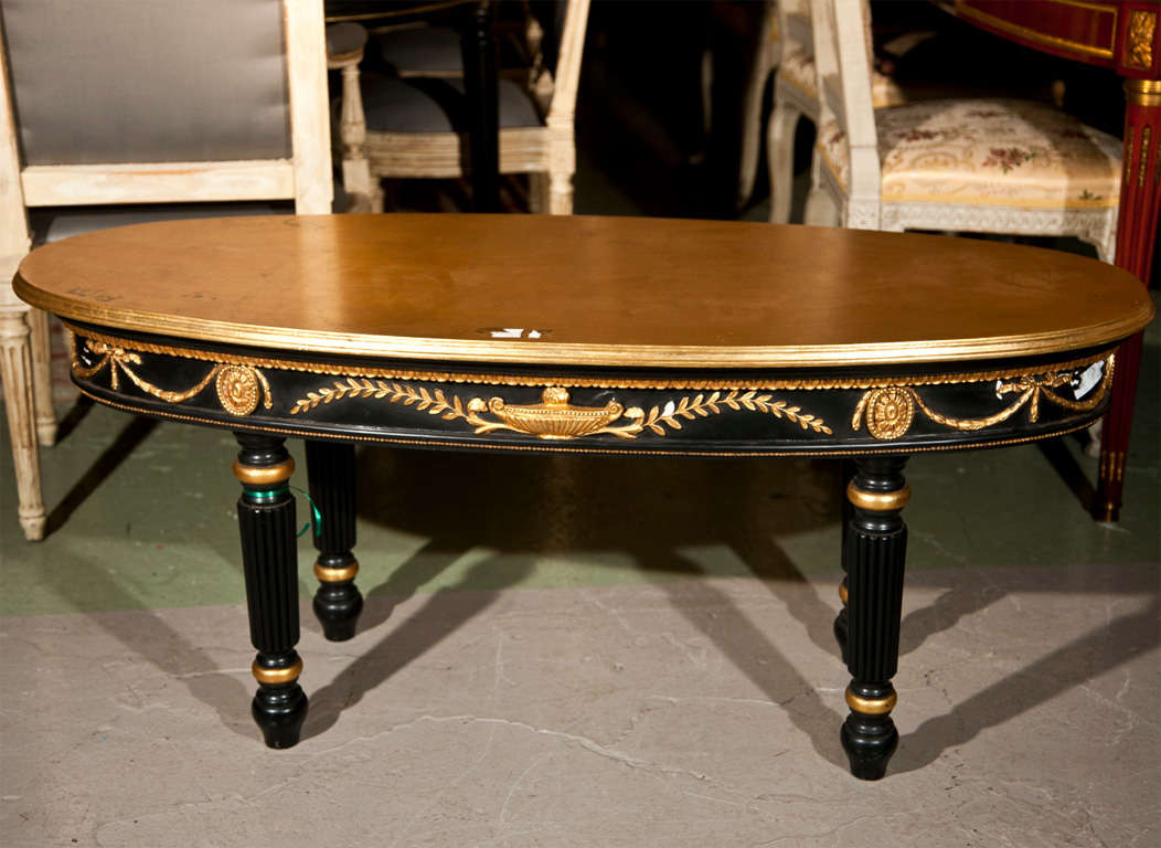 A Louis XVI style ebonized and gilt gold decorated coffee table. The gold-leaf top supported with a carved base. Attributed to Maison Jansen.