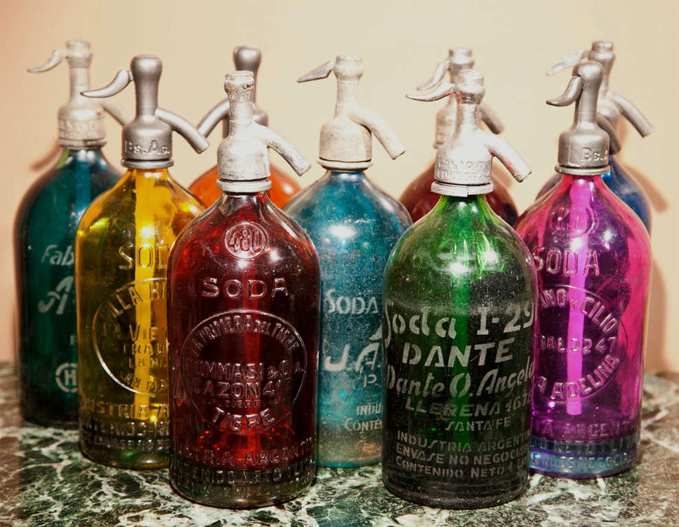 A very large collection of Seltzer bottles from Argentina. Each with a metal top and straw interior. in a variety of colors. Many with raised lettering. Diameters range between 3.5 and 4 inches. Most of 4 inches. Can mix or match. PRICE IS FOR ONE