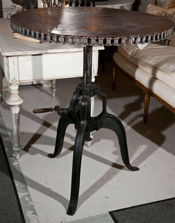 An intriguing vintage industrial steel bar table, the circular top decorated with chain frieze, supported by a single adjustable pedestal and raised on a splayed tripod legs.