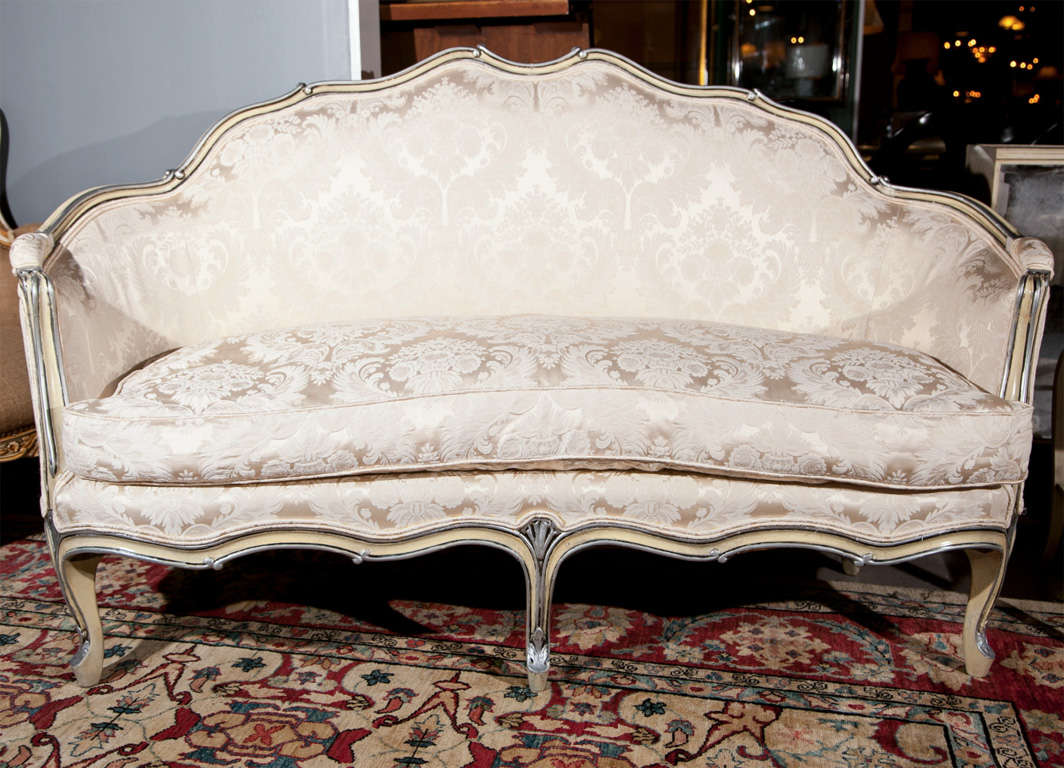 Pair of French Louis XV style settees, beautiful painted frame with parcel silver-leaf, recently upholstered in silk and cushioned seat, raised on cabriole legs. In the manner of Maison Jansen