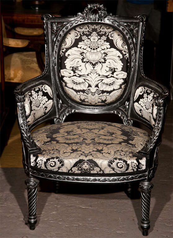 Pair of intriguing French Louis Phillipe style fauteuils, distressed ebonized frame upholstered in the back, arms, and seat in damask. Raised on tapering legs. They are part of the salon suite which completes with a canape, please see another