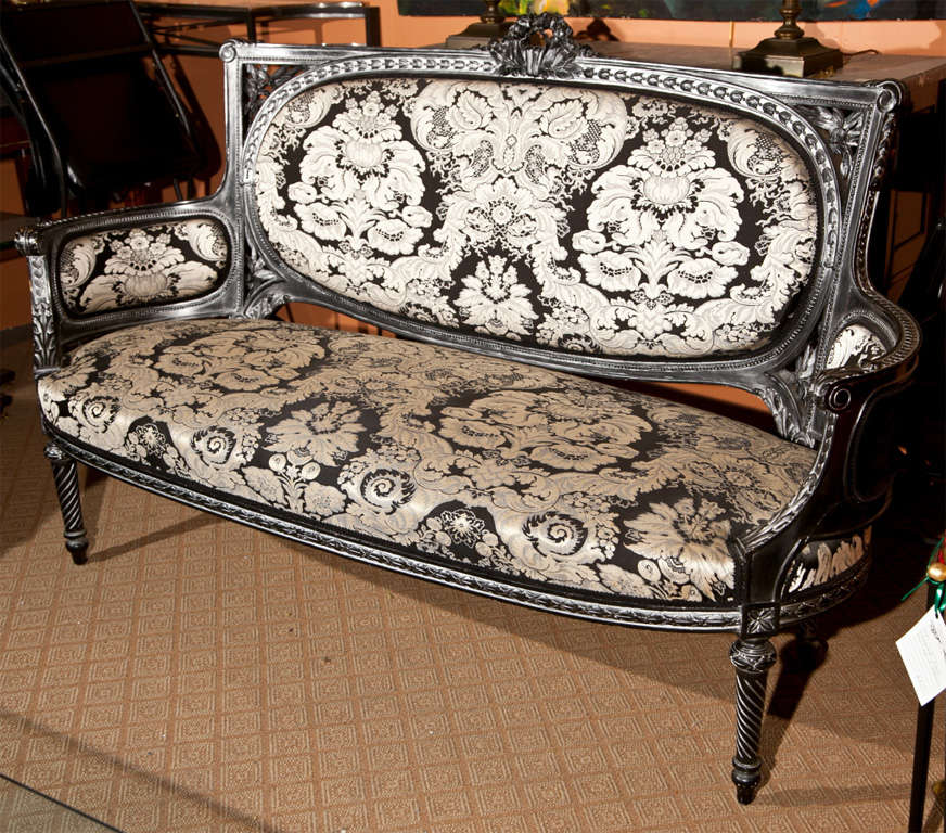 A beautiful French Louis Phillipe style canape, overall distressed ebonized frame, upholstered in the back, arms, and seat in damask, raised on tapering legs. This is part of the salon suite which completes with a pair of fauteuils, please see
