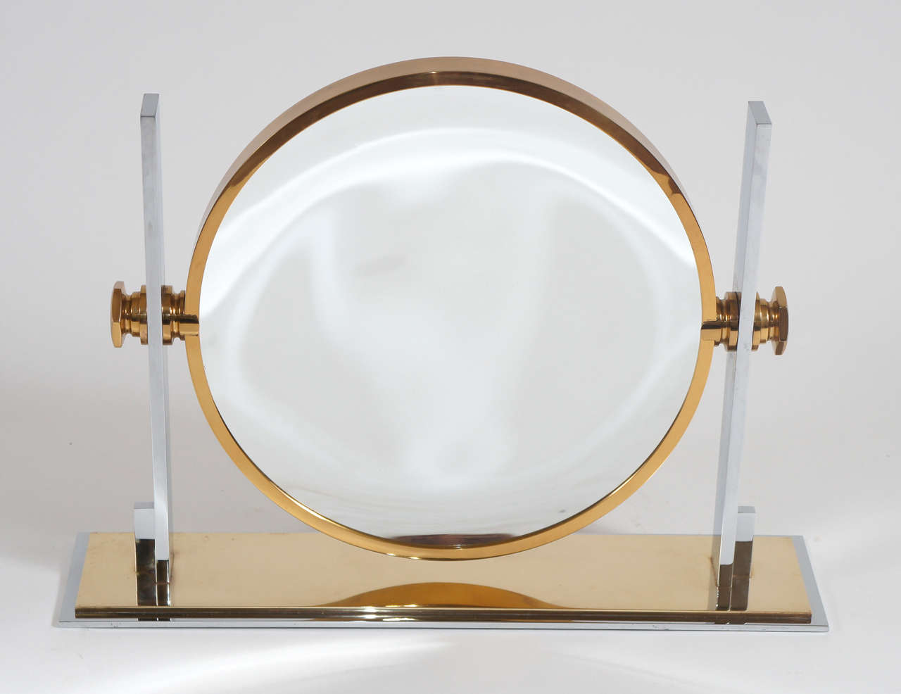Elegant streamlined chrome and brass pivoting double sided table top vanity mirror designed by Karl Springer.  One side standard mirror, the other concave.