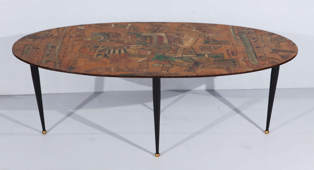 A fabulous laminated Italian coffee table with an Aztec design. It has four pencil legs on brass ball feet. There is a signature on the table top that says 