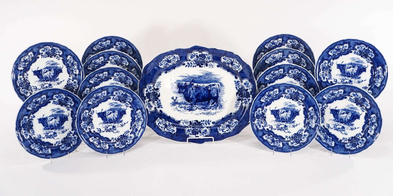 This is a complete and rare set of 12 Doulton Lambeth blue and white transfer dinner plates featuring Scottish Highland Cattle centered in a realistic landscape surrounded by decorative reserves along the border. Artist signed Wilson, the crisp and