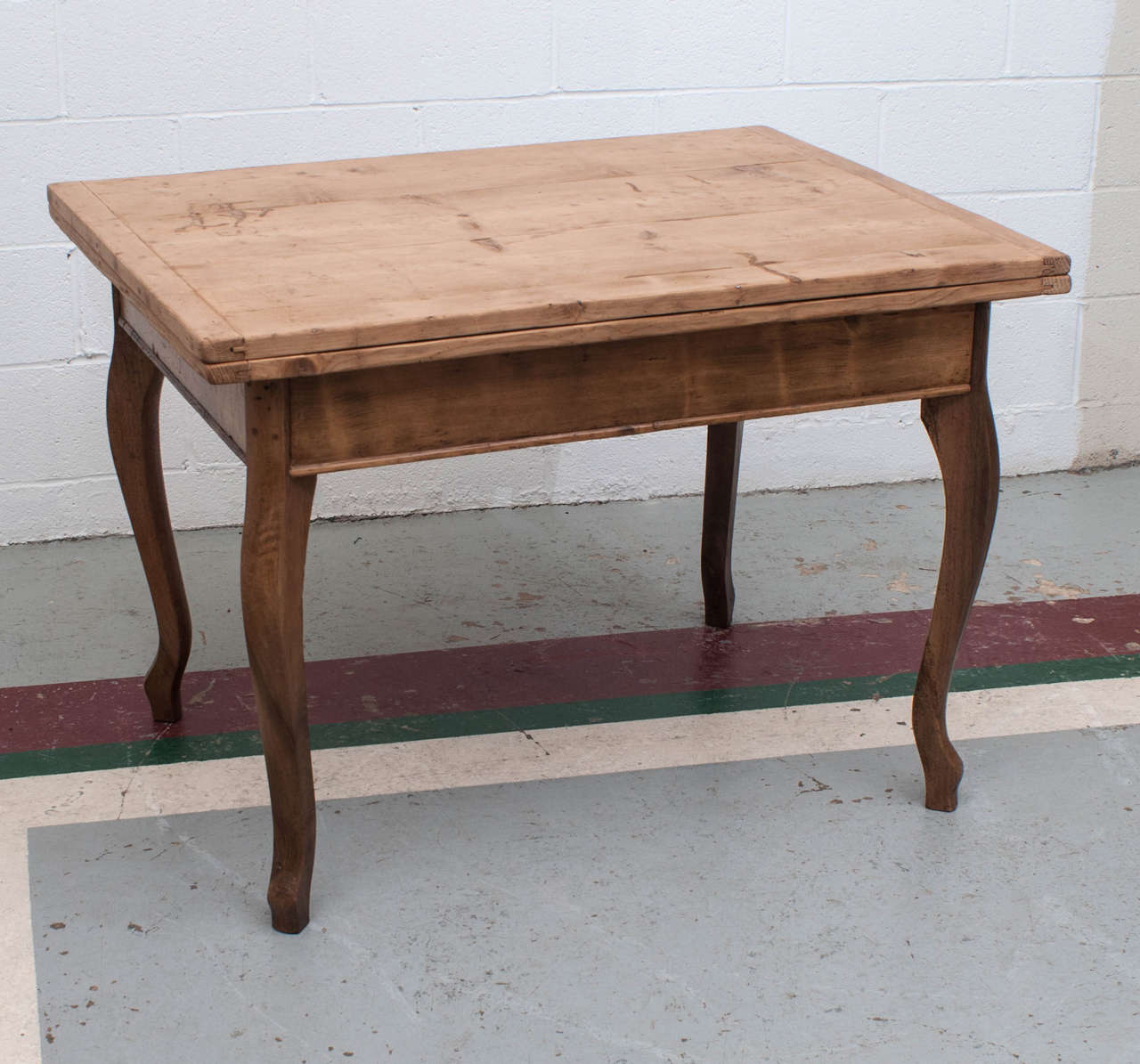 This charming and versatile table has a hinged top which pivots through ninety degrees and opens to twice its closed size.  Beneath the top is a handy storage space.  On four chestnut cabriole legs.