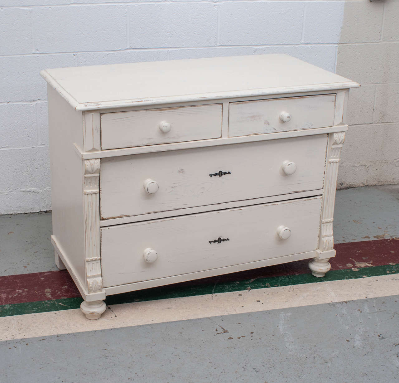 A lovely little pine chest of two short and two long graduated hand cut dovetailed drawers flanked by fluting and acanthus leaf corbels.  This piece is the perfect height for a changing table.  Recent distressed hand paint.