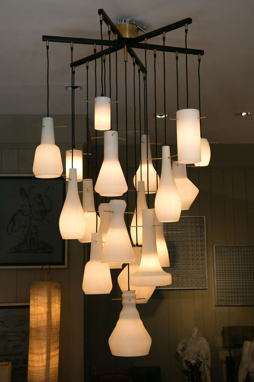 That unique chandelier is composed 19 vintage opaline glass shades from Italian lighting from the 1950s all in various shapes and sizes.
The structure is newly done with black lacquered metal and brass details.
This piece is signed by the Italian