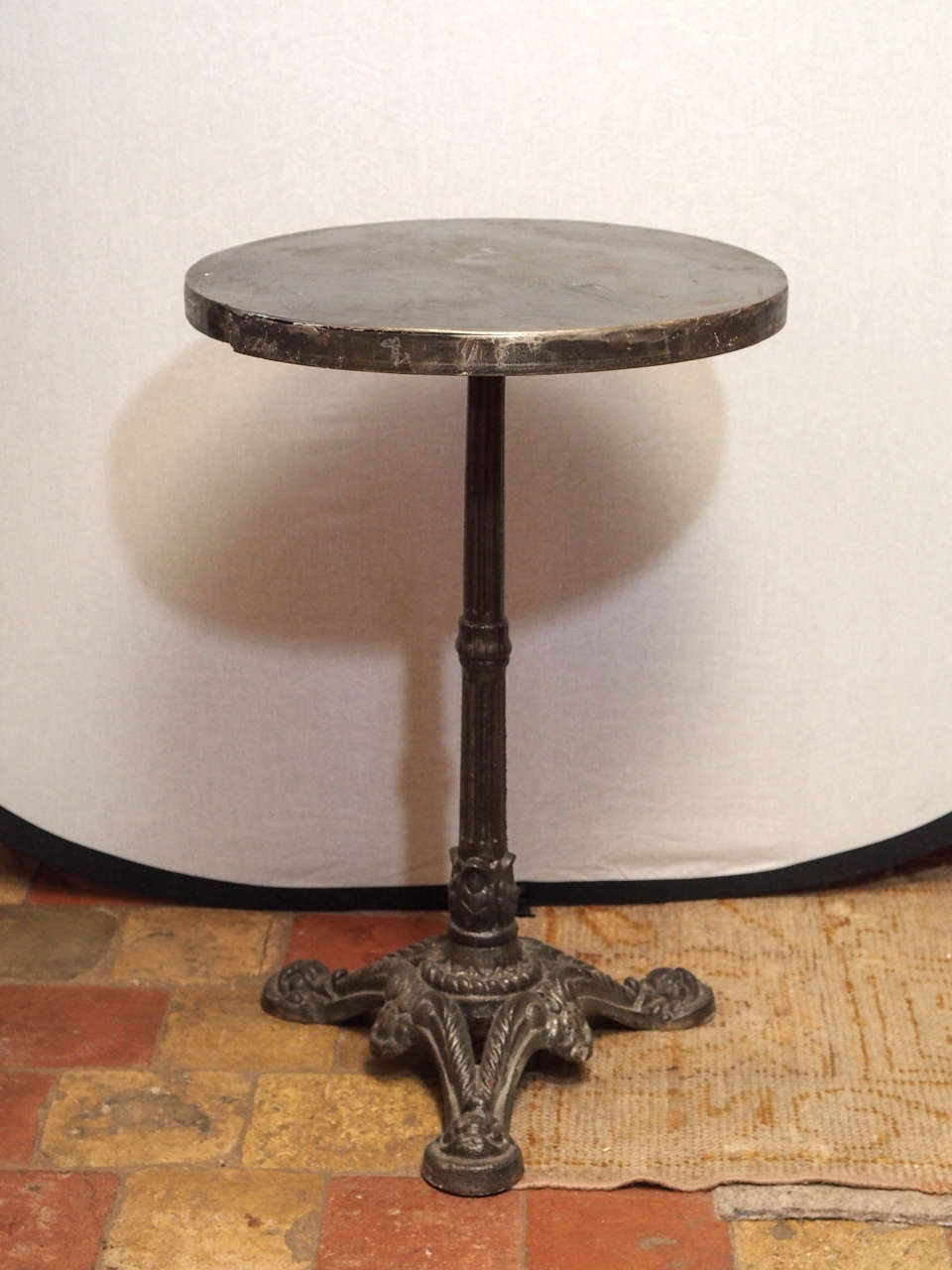 French round bistro table with a metal top and pedestal base.