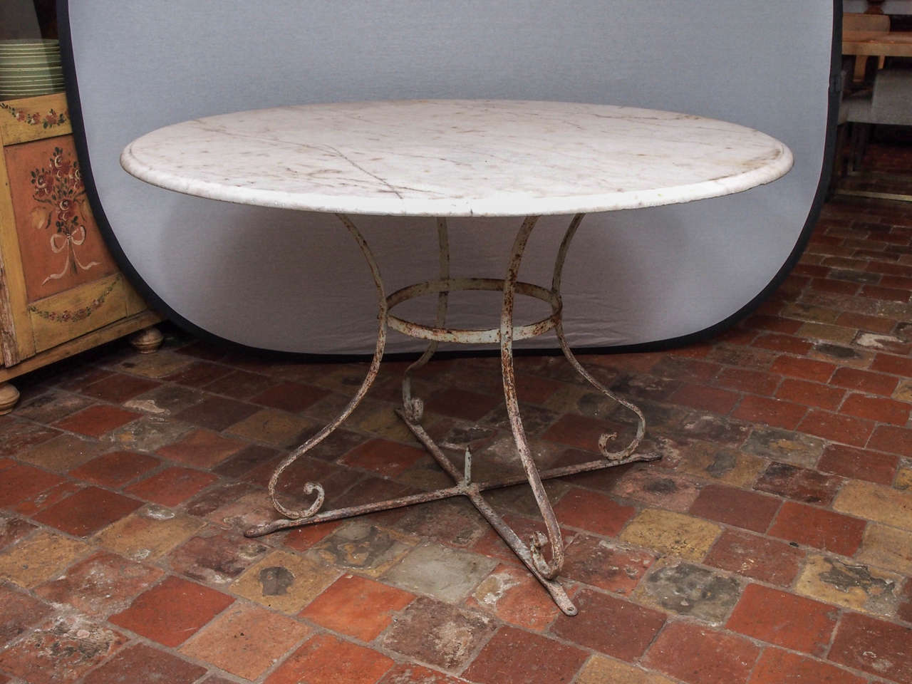 French round bistro table with a marble top and metal pedestal Base.