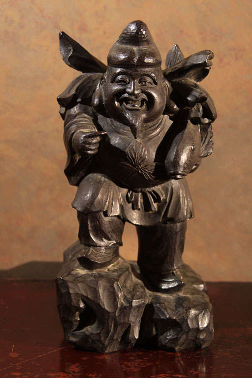 Japanese cast bronze statue of Ebisu, Shinto God of honest dealings, food, fisherman and general prosperity. Ebisu is depicted standing on a rocky outcropping with well carved face wearing flowing robes, auspicious knotted belt and characteristic