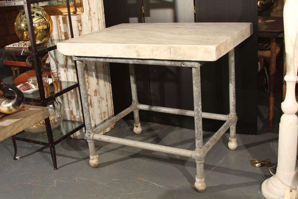 industrial metal base with white porcelain feet topped with 3 inch solid marble slab. Perfect kitchen island , work /serving station.