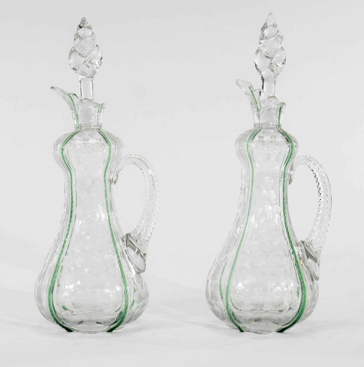 This beautiful pair of hand blown crystal decanters are very well matched with applied twisted handles. Each bottle has internally decorated apple green inclusions along the four lobes and are further decorated with wheel cut thistles. These make a