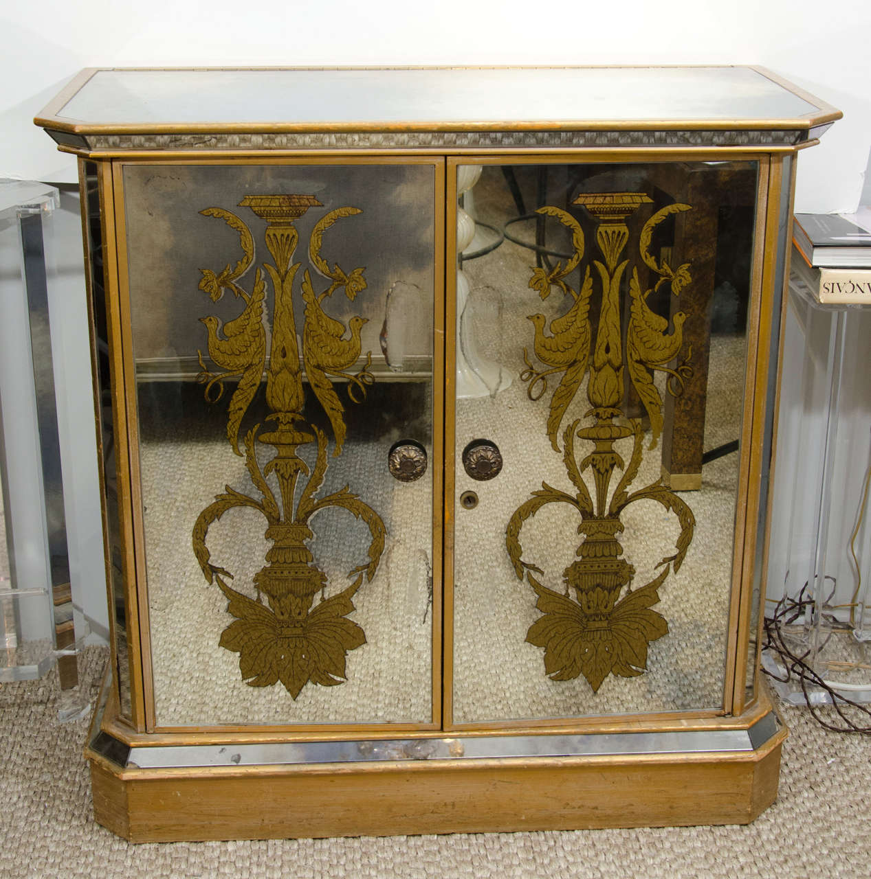 This mirrored and painted bar cabinet is a lovely place to serve cocktails.  The cabinet has two doors in front that open to reveal storage for glassware and supplies.  The top portion contains two storage compartments for bottles, as well as a