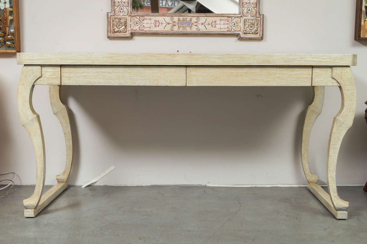 Beautiful hand-carved crackle glaze two-drawer desk with stylized Egyptian influenced legs, featuring two drawers. The thick top has canted detailing in the corners.
This desk was designed by John Hutton in the 1970s for Randolph and Hein in San