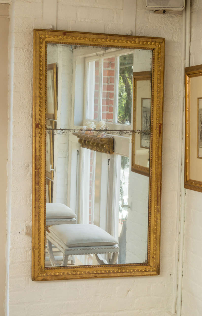 18th century Neo-Classical Italian hand-carved giltwood trumeau mirror with original mirror plate.

The frame is beautifully carved with combinations of beading, featuring the original mirror plate in two parts, nicely distressed with elements of