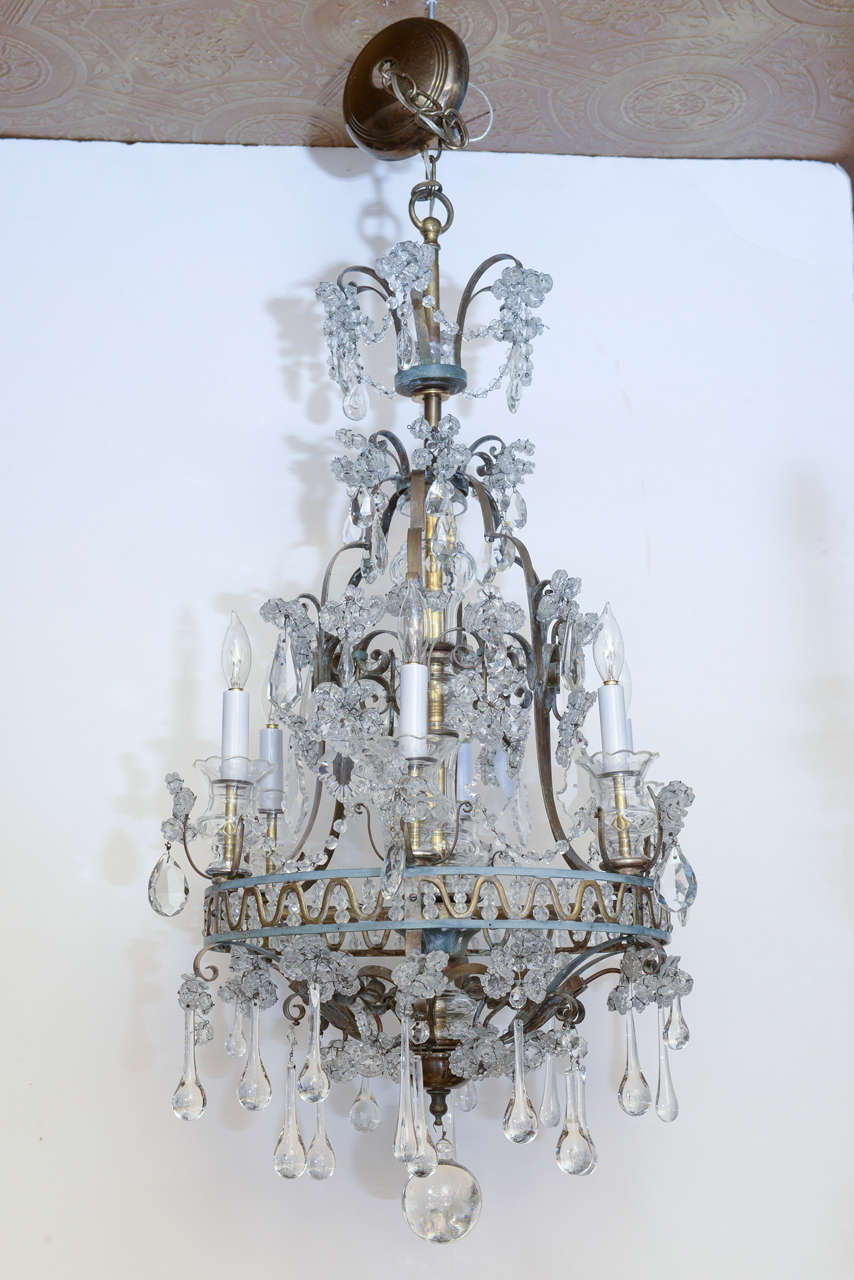 Rare form chandelier, of painted and polished bronze, attributed to Maison Baguès; having a knopped central standard, supporting an outer ring decorated with a brass wave-meander, holding six candles, the entire fixture affixed with crystal-cluster