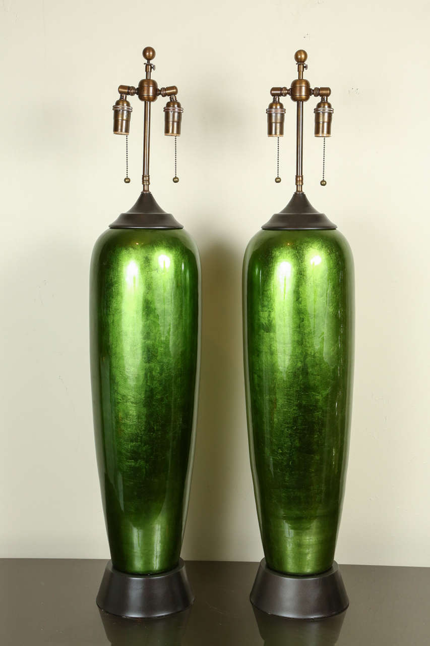 Pair of enormous bullet shaped glazed ceramic lamps. The beautiful glossy glaze leaf finish has a slightly metallic quality. They are newly rewired with bronze double clusters and mounted on antiqued brass painted finish bases.