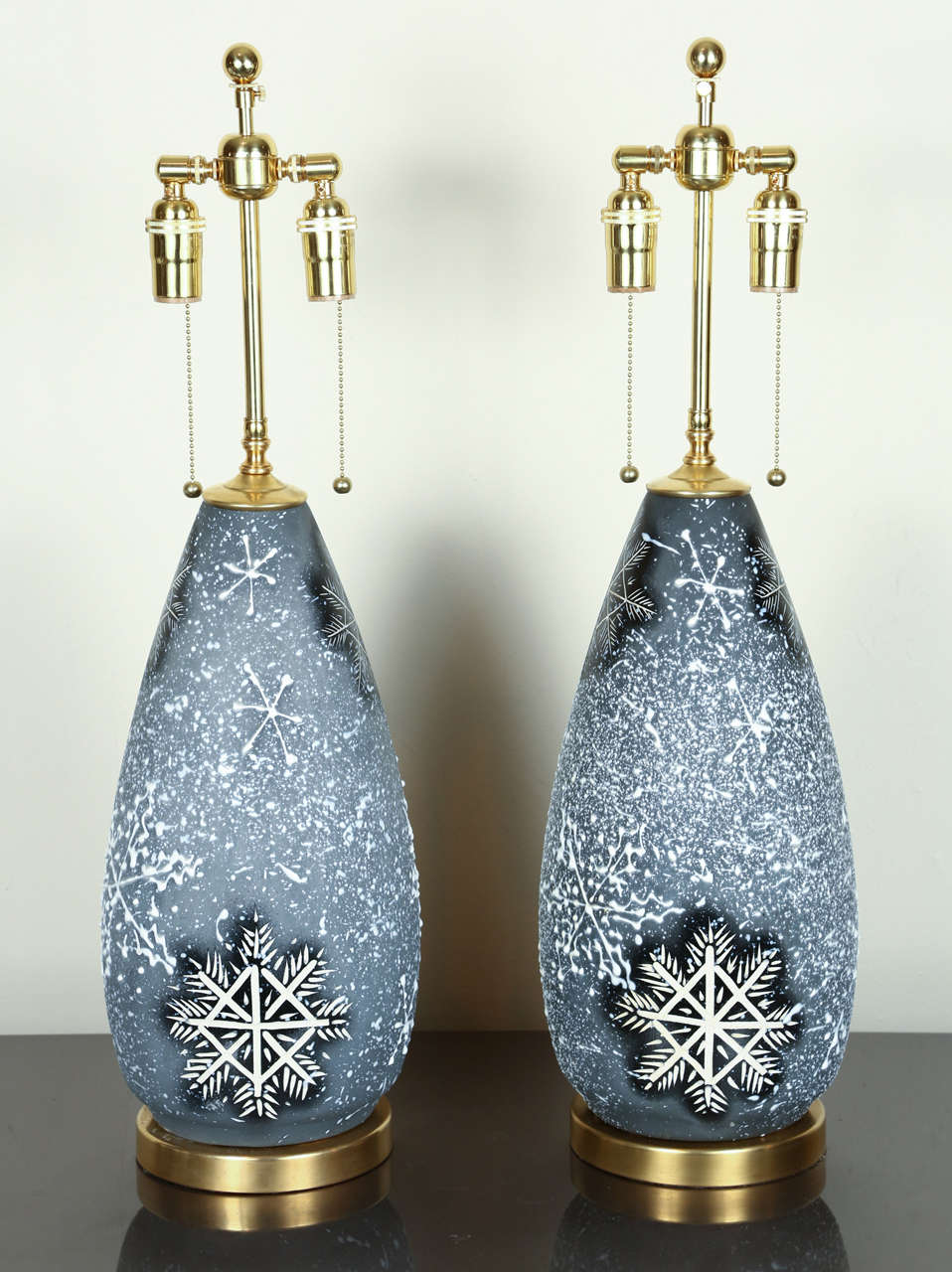 Pair of lovely ceramic lamps with a whimsical snowflake design.
The snowflake design is both incised and drip glazed on the surface and they are newly rewired with brass double clusters that take standard light bulbs.
