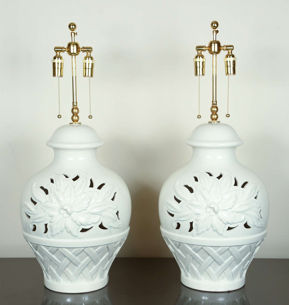 Pair of very large glazed ceramic lamps with a basket-of-flowers embossed and pierced design.  They are newly rewired with brass double clusters and silk rayon cord.