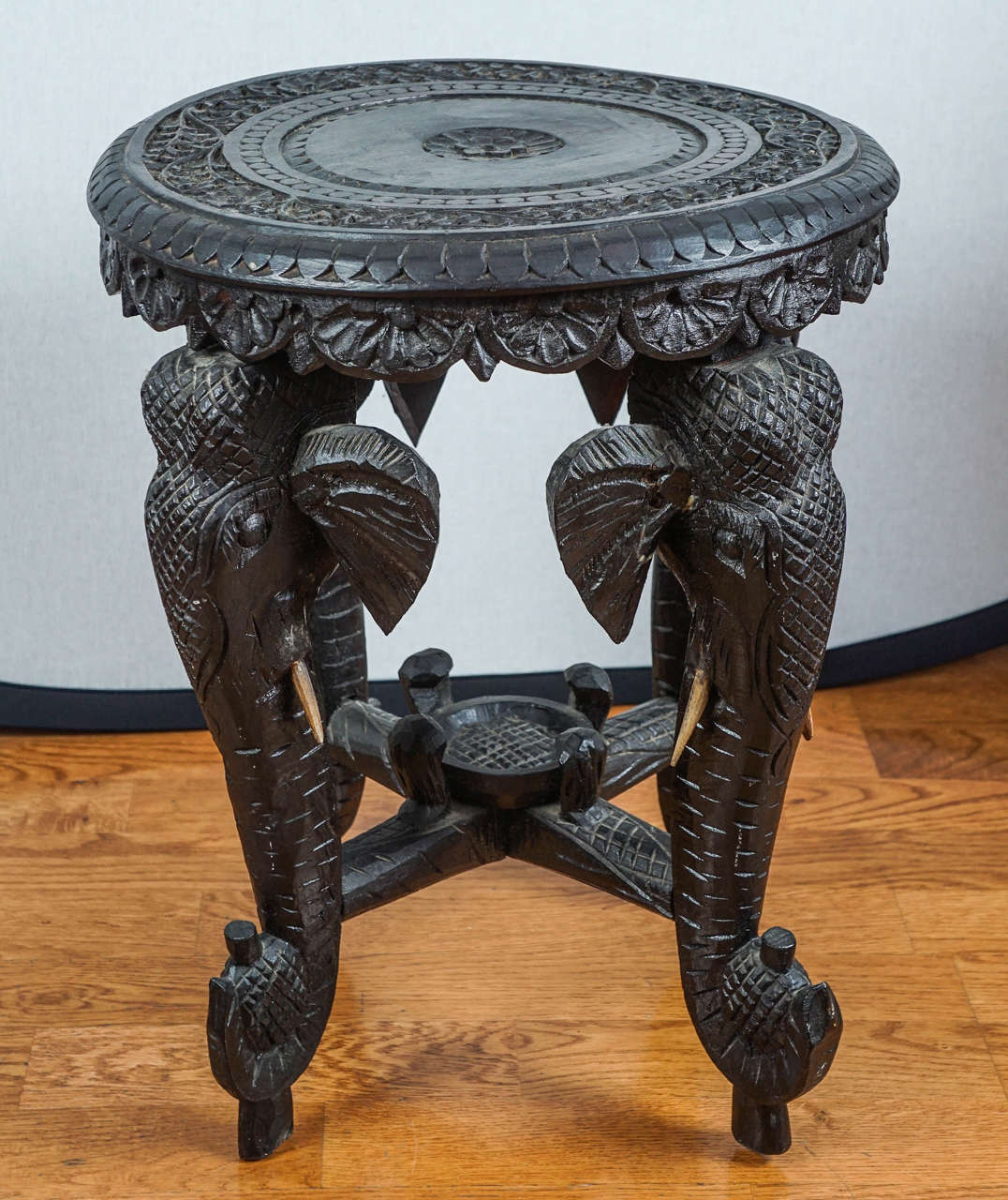Vintage, intricate, hand carved round wooden, ebonized table.
Four elephant heads with faux ivory tusks form the legs of this unique table.