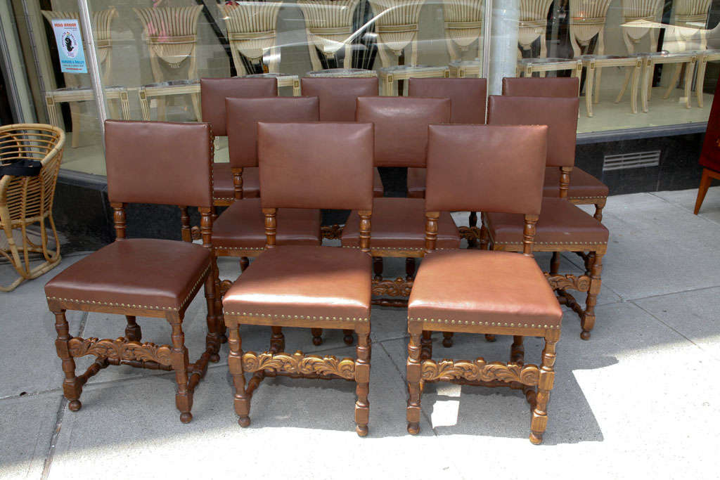 Set of ten dining chairs, Renaissance Revival style, in oak with brown leather upholstery, carved chair rails and brass studded leather.