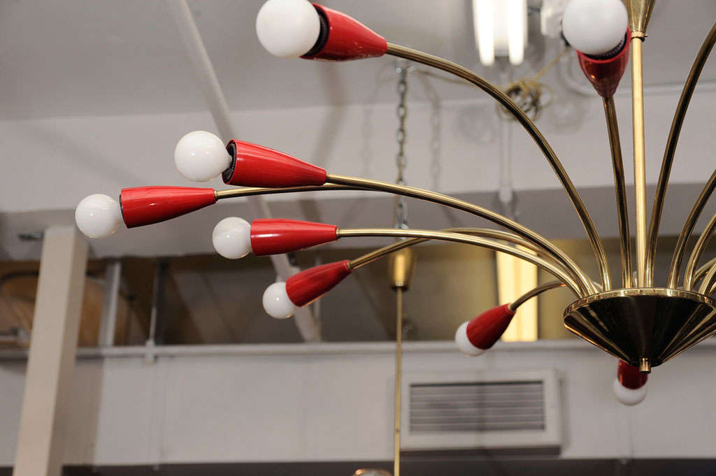 Italian sixteen arm spider chandelier in polished brass, with red enameled light holders. Arms are in alternating lengths. Possibly by Stilnovo.