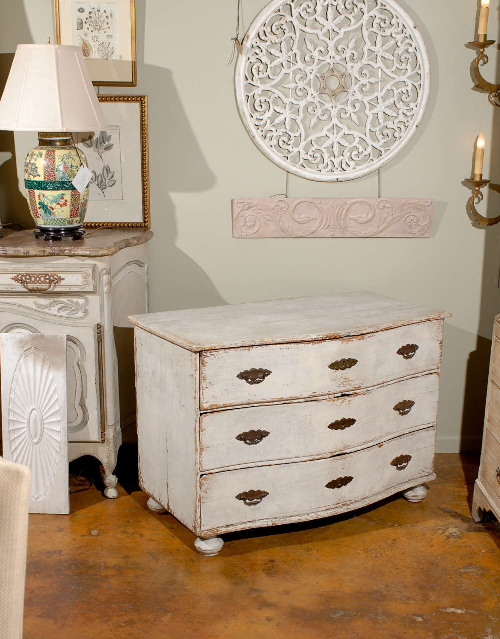 A Swedish 18th century Baroque period three-drawer painted pine chest with serpentine front and bun feet. This swedish light grey painted chest of drawers features a shaped rectangular top sitting above a serpentine front. Each hand-cut dovetailed