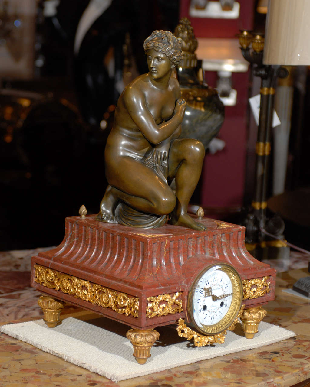 Très belle horloge en bronze doré, bronze patiné et marbre de Marlin & Cottin, 26 rue Amelot, Paris. Le corps de la pendule en marbre rouge est orné de guirlandes en bronze doré et repose sur des pieds toupies. Au sommet, une statue patinée