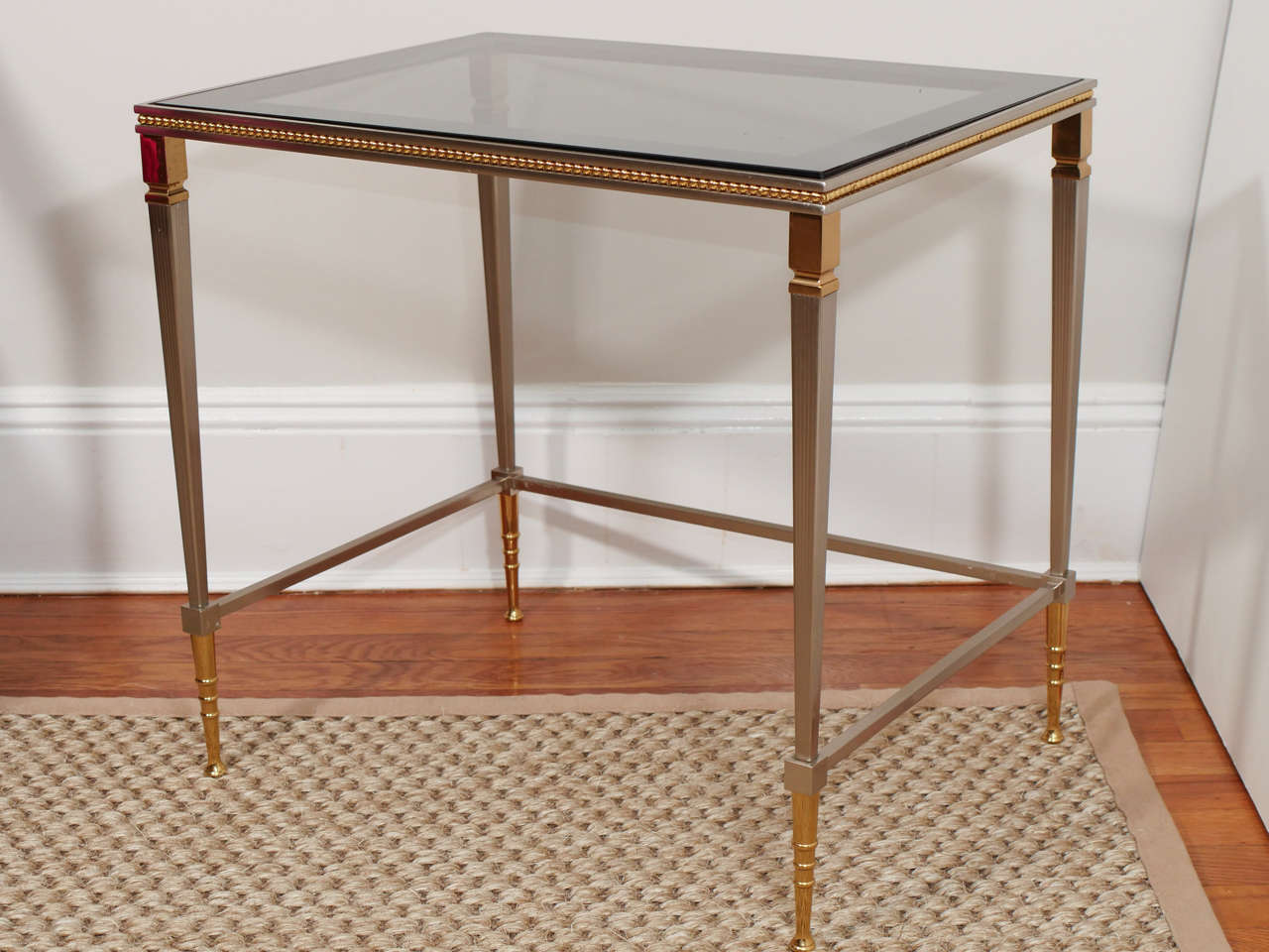 A set of three Jansen style nesting tables in brass and nickel with tinted glass tops.
