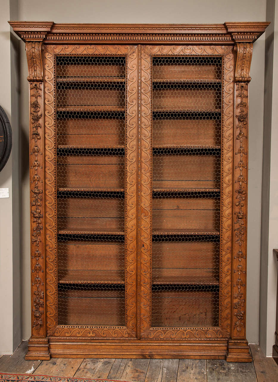 In the manner of William Kent, each moulded cornice with dentil frieze
above a pair of wirework panelled doors carved with Vitruvian scroll
borders, opening to adjustable shelves, acanthus carved scroll terminals
above floral branch carved
