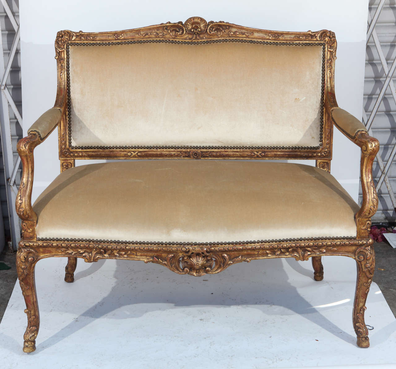 Late 18th-Early 19th century French Regency finely carved giltwood settee. Upholstered and detailed with nailheads.