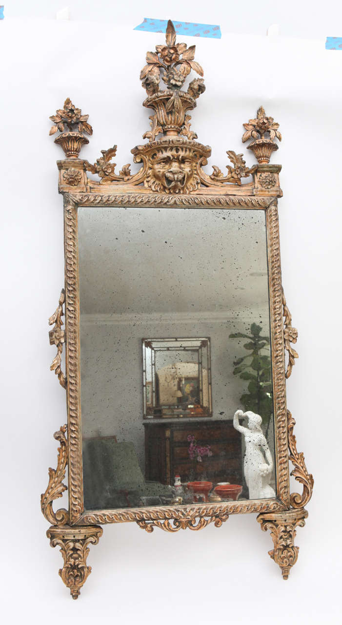 Late 18th century Italian giltwood and painted mirror with lion's head and flower basket motif.