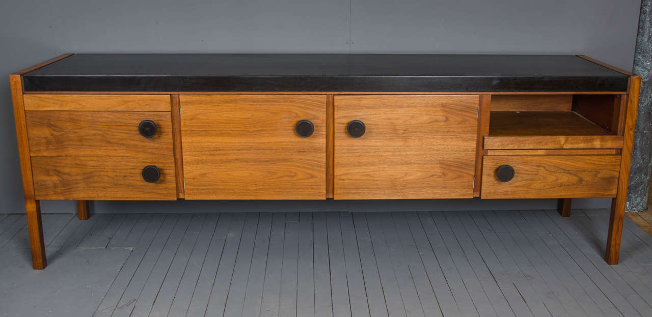 This beautiful contemporary sideboard, circa 1980s, features an ebonized finish top and large turned, round handles. It was designed by Jens Risom, a Danish American furniture designer of the period, and has several labels inside the piece. The