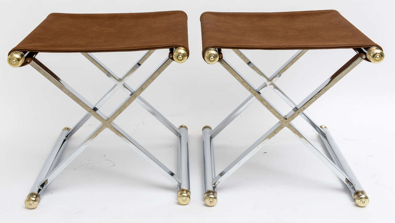This handsome pair of X-base stools are the Hollywood Regency take on the campaign stools of the 18th and 19th centuries. They are in polished chrome with polished brass finials and upholstered in a faux-suede fabric.

Note: There is a small stain