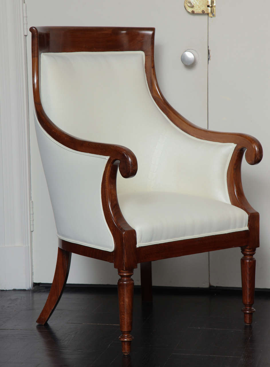 Pair of late 19th century mahogany armchairs in scrolled arms with tapered legs and concave back.