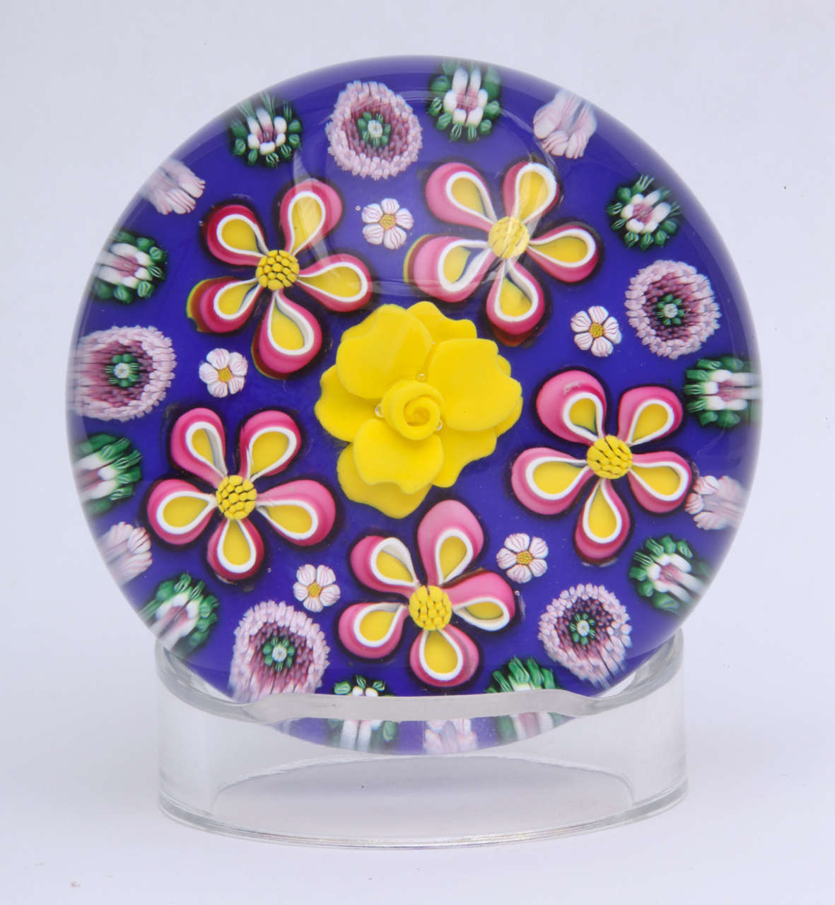 A beautiful floral and millefiori paperweight by Drew Ebelhare and Sue Fox, the central yellow flower surrounded by a row of red, white and yellow flowers and millefiori canes on a blue ground