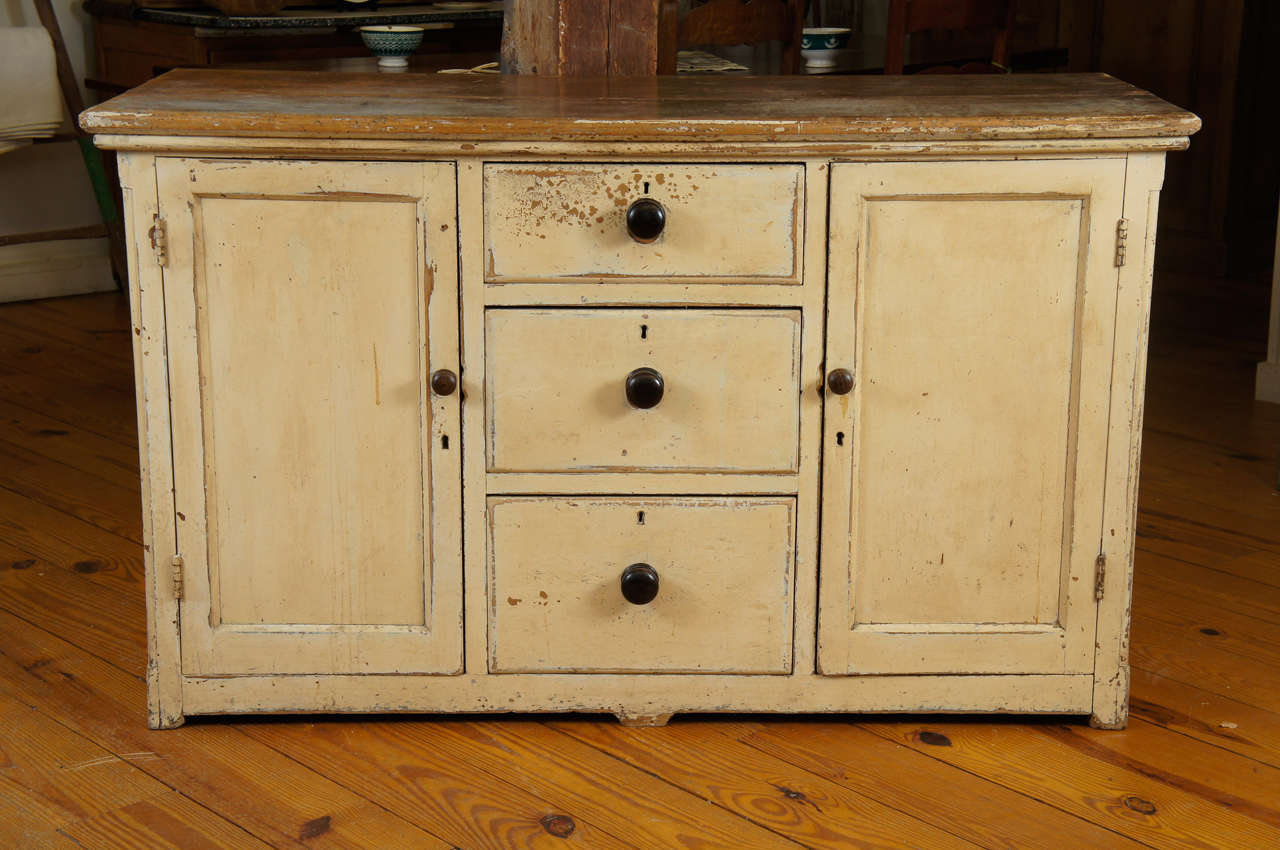 Original cream/ butter paint and Chocolate color knobs accent this piece. The top is worn and the piece is all about country This could be a very nice kitchen piece but is useful anywhere in your home.We think this piece may have come out of a shop