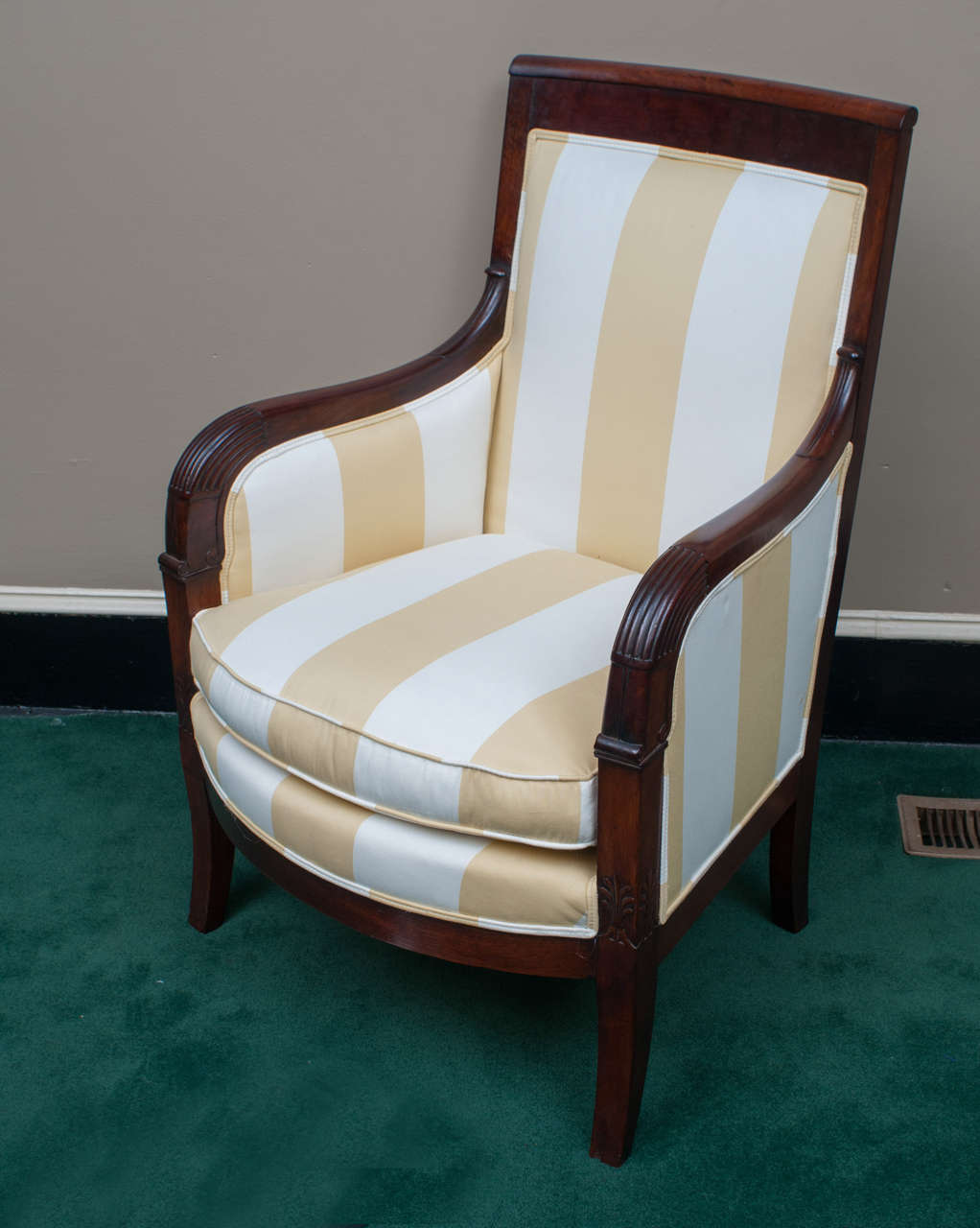 This very comfortable chair has excellent proportions. The rich, warm French-polished mahogany frame has multiple understated highlights including a curved flame mahogany back rail, reeded sections at the elbows and wrists of the arms, and carved